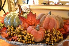 a bowl filled with pumpkins and gourds sitting on top of a table