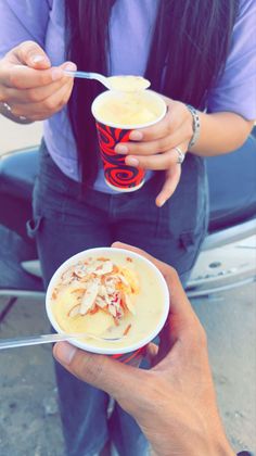 a woman holding a cup of soup in her hand