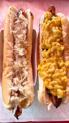 two hotdogs with macaroni and cheese on them sitting next to each other