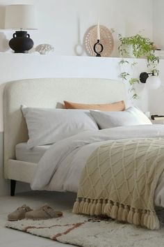 a bed with white sheets and pillows in a room