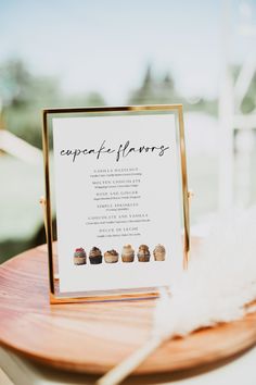 a table with a sign and some cupcakes sitting on it's side