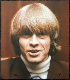 an old photo of a man with blonde hair and a turtle neck sweater, looking at the camera