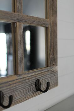 an old window is hung on the wall with two hooks and a mirror behind it