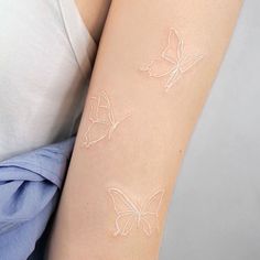 a woman's arm with two white butterflies painted on the back of her arm