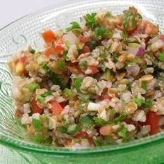 a green bowl filled with rice and veggies on top of a glass table