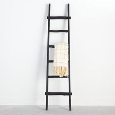 a ladder leaning against a white wall with a towel on it's back end