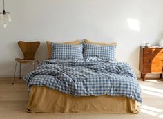 a bed with blue and white checkered comforter in a room next to a chair