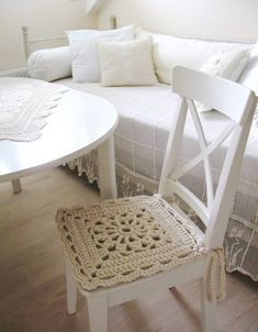 a crocheted chair sits in front of a white couch and table with pillows on it