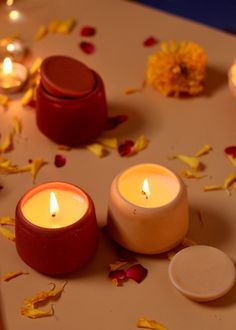 three candles sitting on top of a table covered in petals