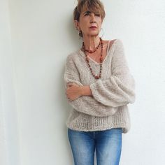 a woman leaning against a white wall with her arms crossed and looking off to the side