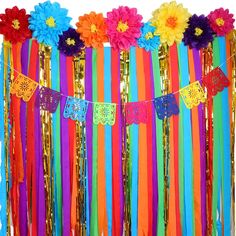 colorful streamers and paper flowers are hanging from the side of a party decoration wall