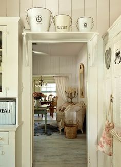 an open door leading to a living room with white walls and wood paneled floors