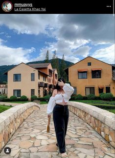 a woman walking across a stone walkway in front of some houses