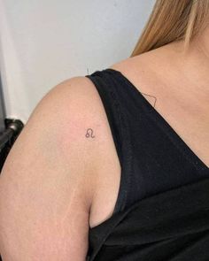 a woman with a small tattoo on her left shoulder and the letter s in cursive writing