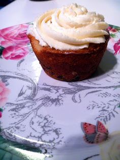 a cupcake with white frosting on a floral plate