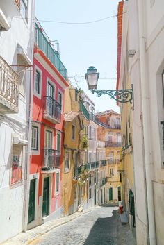 an alleyway with several buildings painted in different colors and balconies on each side