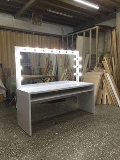 a vanity table with lights on it in front of a pile of wooden planks