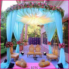 an outdoor wedding setup with blue drapes and pink flowers