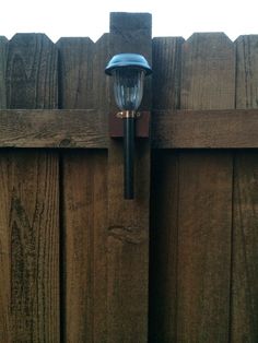 a close up of a light on the side of a wooden fence