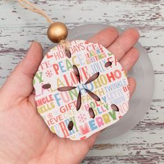 a hand holding a paper ornament with words on it