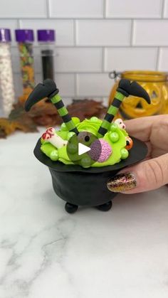 a hand holding a small black bowl filled with halloween decorations