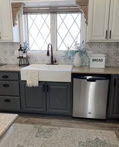 a kitchen with gray cabinets and white walls, an open window over the dishwasher