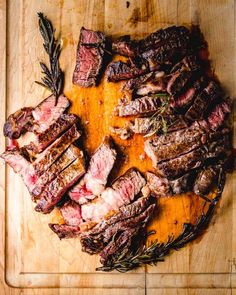 steaks on a cutting board with rosemary garnish