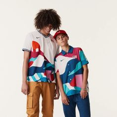 two young men standing next to each other in front of a white wall wearing nike clothing