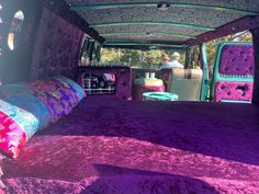 the inside of a van with purple carpet and colorful pillows on it's bed