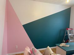 a living room painted in shades of blue, pink and white with a ladder leaning against the wall