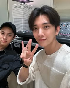 two young men posing for the camera in front of sound mixing equipment with their fingers up