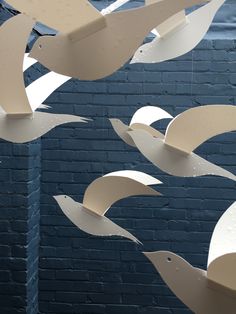 several white birds are flying in the air near a brick wall with blue paint on it