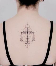 the back of a woman's neck with a tattoo on it that has an image of a scale and hourglass