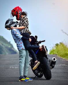 two people standing next to a motorcycle on the road