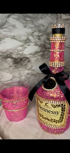 a pink bottle and two glasses on a marble table with a black ribbon around it