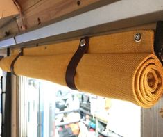 a yellow blanket hanging from the side of a wooden beam in front of a window