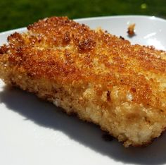 a piece of fried food on a white plate with green grass in the back ground