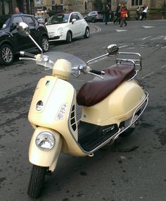 a motor scooter parked on the side of the road in front of some cars