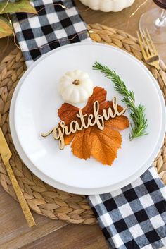 a white plate topped with an orange leaf and the word grateful