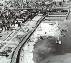 an aerial view of a city with construction in the foreground and water on the far side