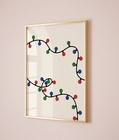 a framed art piece hanging on the wall with christmas lights in it's frame