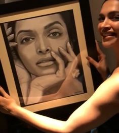 a woman holding up a drawing of a woman's face in front of her