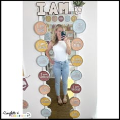 a woman taking a selfie in front of a wall decorated with circles and words