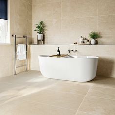 a bath tub sitting in the middle of a bathroom next to a window and tiled walls