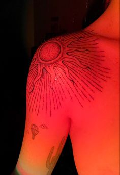 the back of a man's arm with sun and stars tattoo on his left shoulder