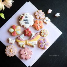 some decorated cookies are sitting on top of a piece of paper next to flowers and seashells