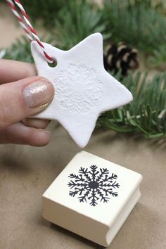 a hand holding a white ornament with a black snowflake on it