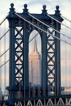 black and white photograph of the empire state building from across the brooklyn bridge in new york city