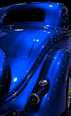 a shiny blue car parked in front of a black background with other cars behind it