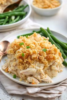 a white plate topped with green beans and chicken casserole next to another dish